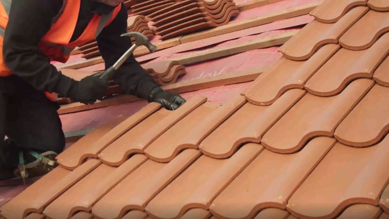Roofer installing new roof tiles on a residential pitched roof